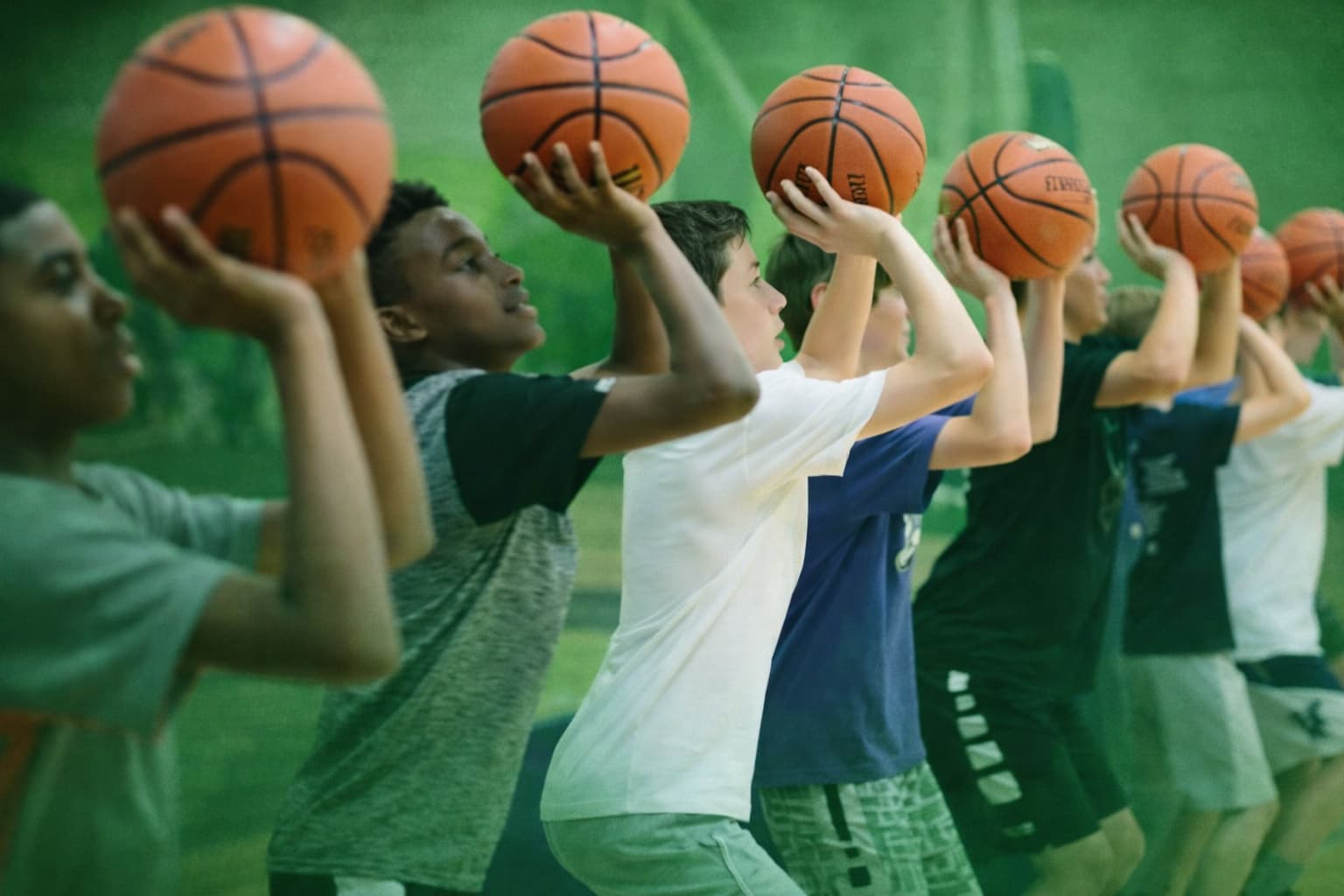 Group of kids shooting basketballs during coaching session