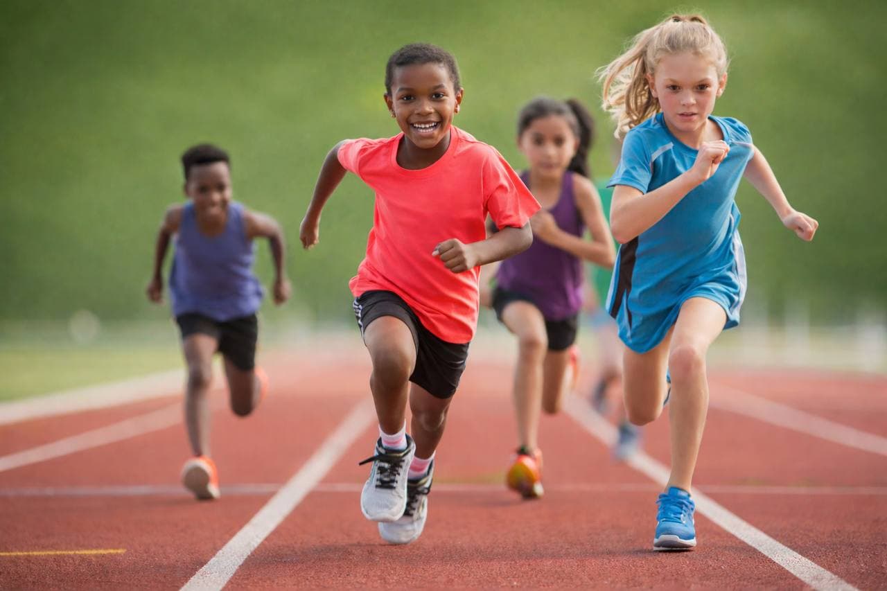 Youth track athletes sprinting on a marked running track